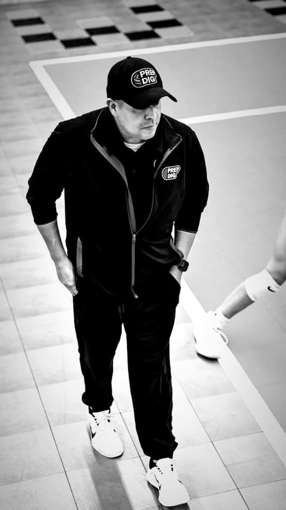 Coach Mike DZ standing on a volleyball court, photographed in black and white